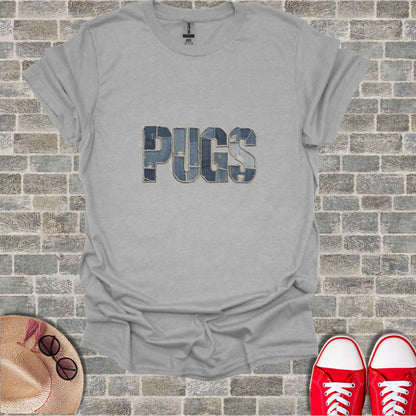 Gray t-shirt with "PUGS" in denim letters on a brick background.