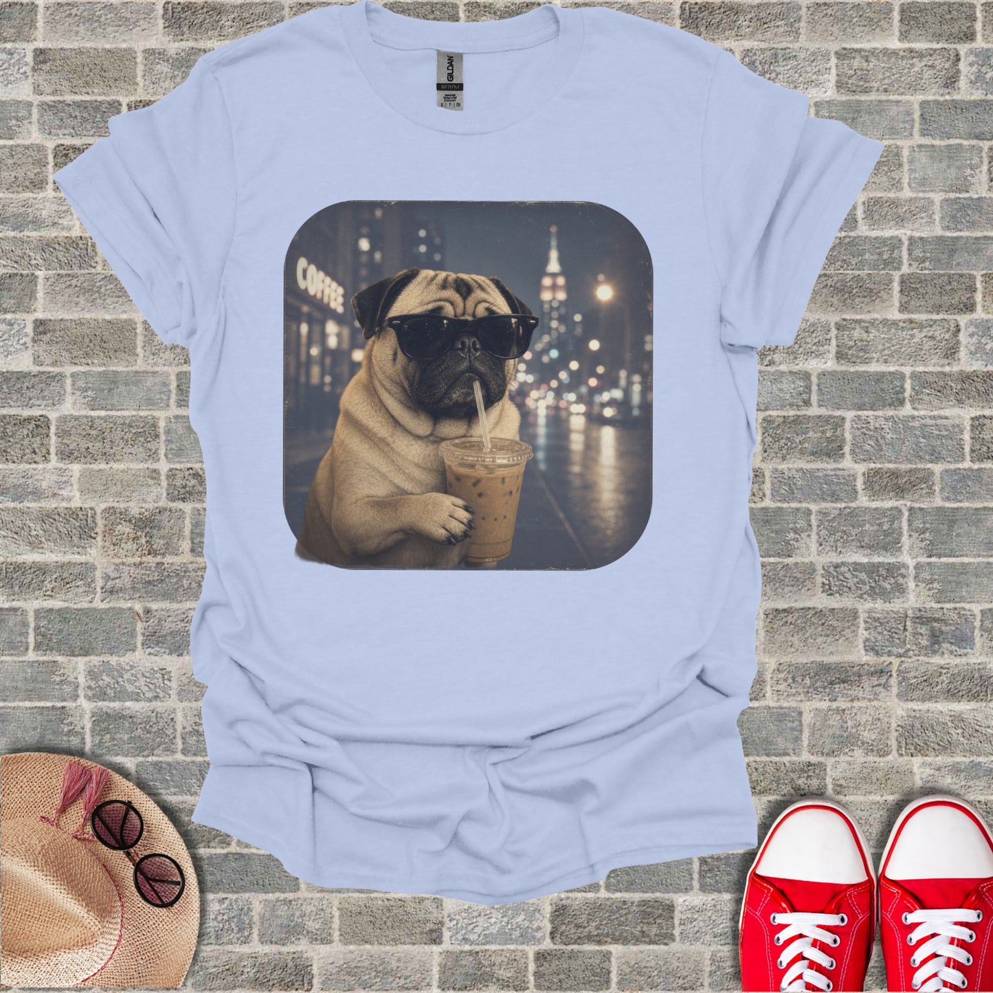 Pug wearing sunglasses drinks iced coffee in front of a city at night.