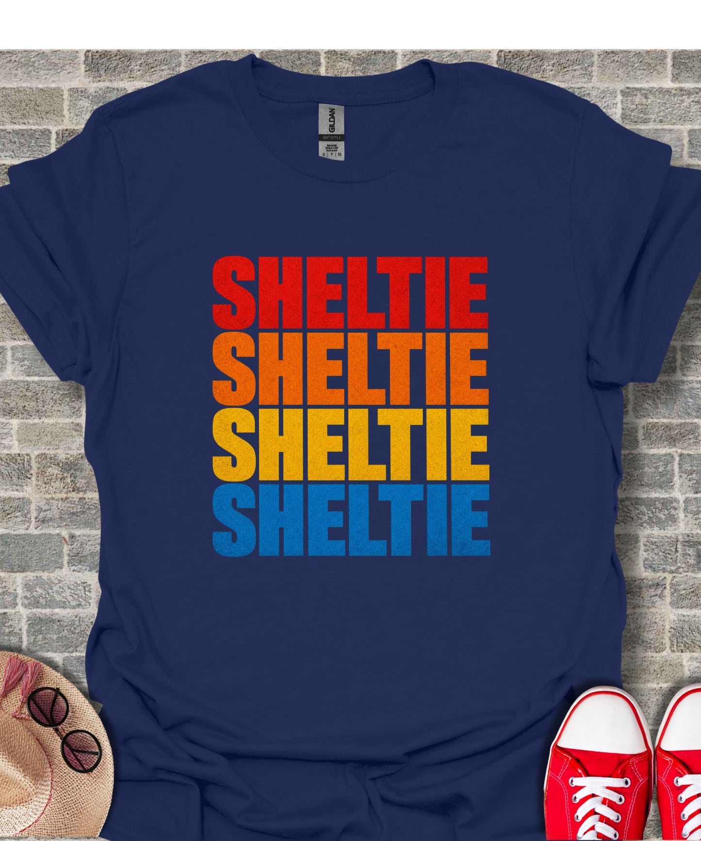 Navy t-shirt with "SHELTIE" repeated four times in red, orange, yellow, and blue.