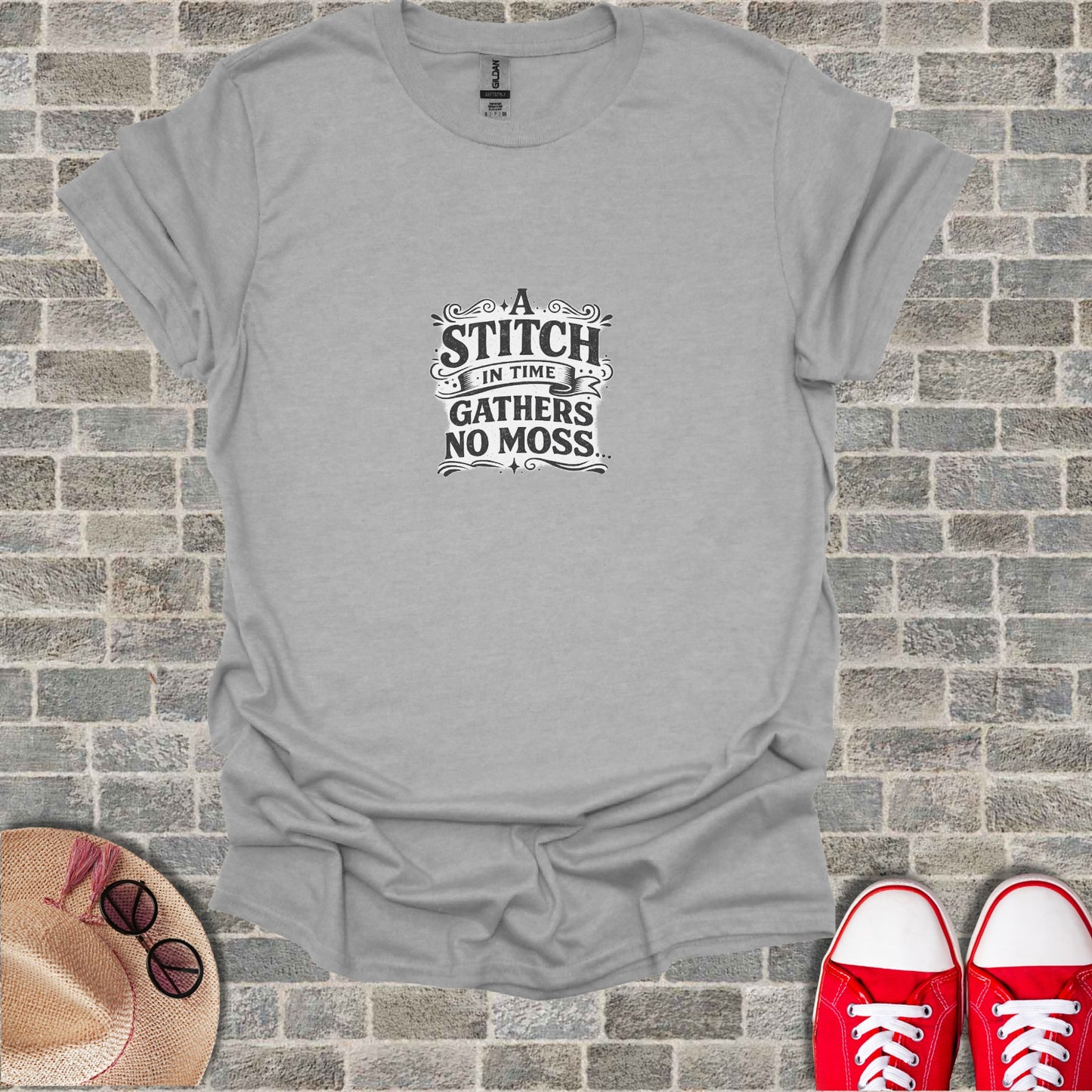 Gray t-shirt with "A stitch in time gathers no moss" text on chest.