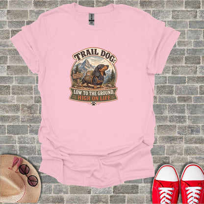 Trail Dog: Low to the ground, high on life graphic on a pink t-shirt.
