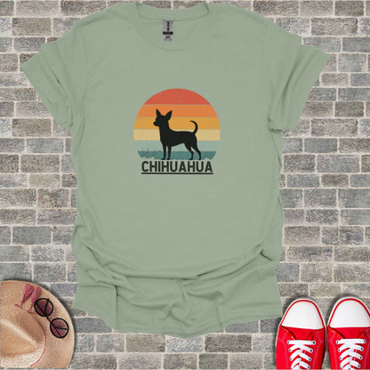 Chihuahua silhouette against a sunset graphic on a light green t-shirt.