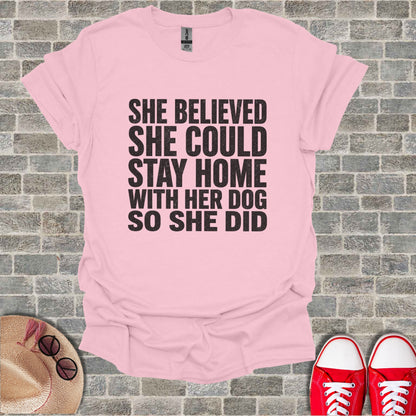 Pink t-shirt with black text: "She believed she could stay home with her dog so she did."