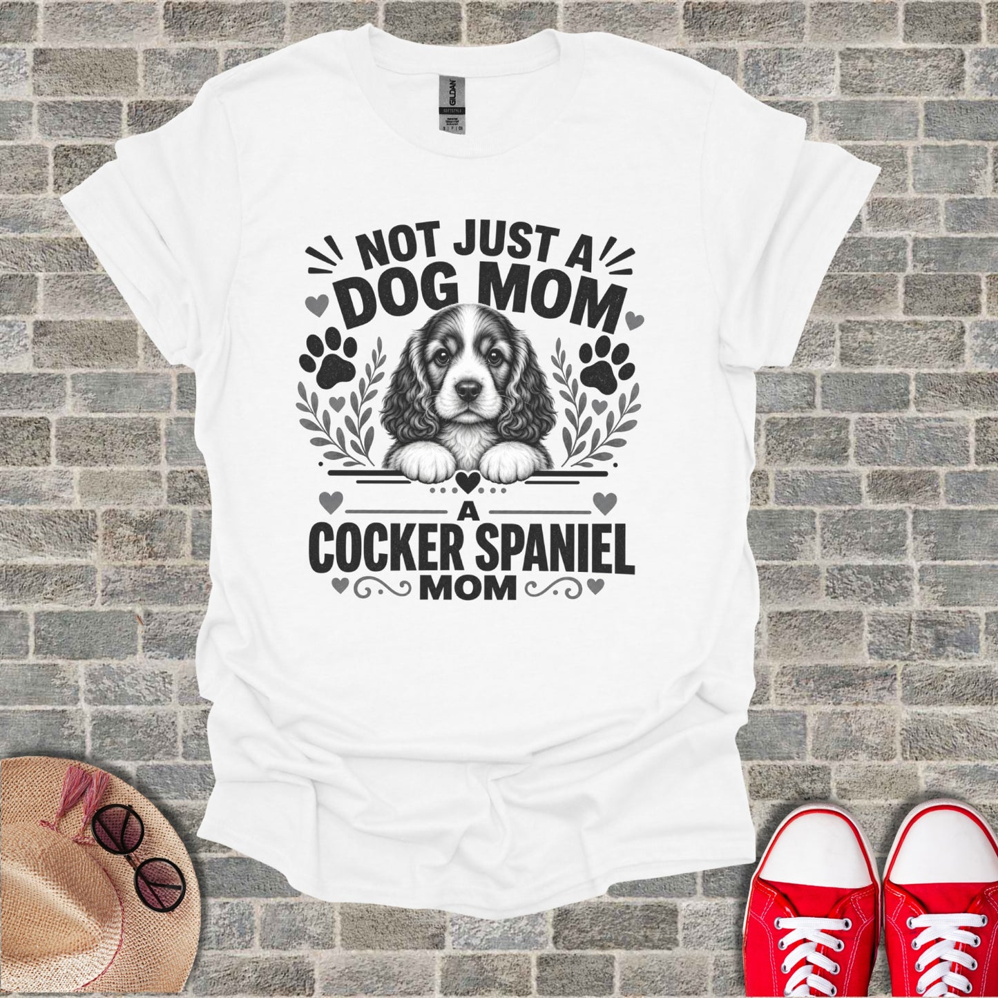 White t-shirt with "NOT JUST A DOG MOM A Cocker Spaniel MOM" text and dog graphic.
