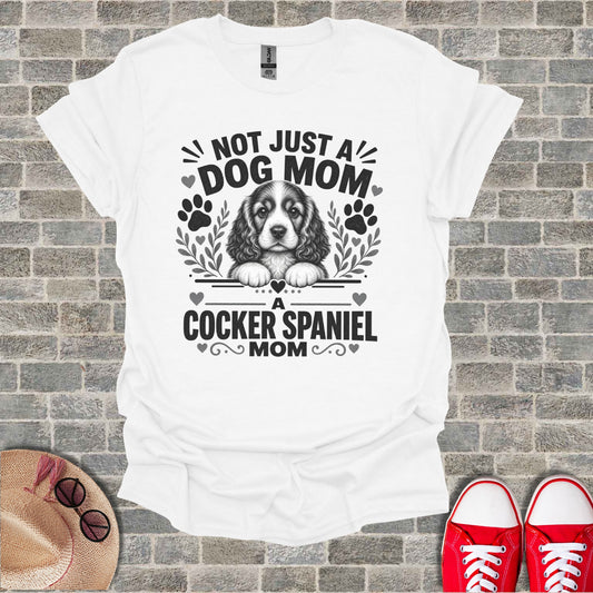 White t-shirt with "NOT JUST A DOG MOM A Cocker Spaniel MOM" text and dog graphic.