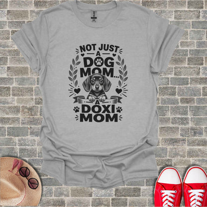Grey t-shirt with text "Not Just A Dog Mom... A Doxi Mom" and dachshund graphic.