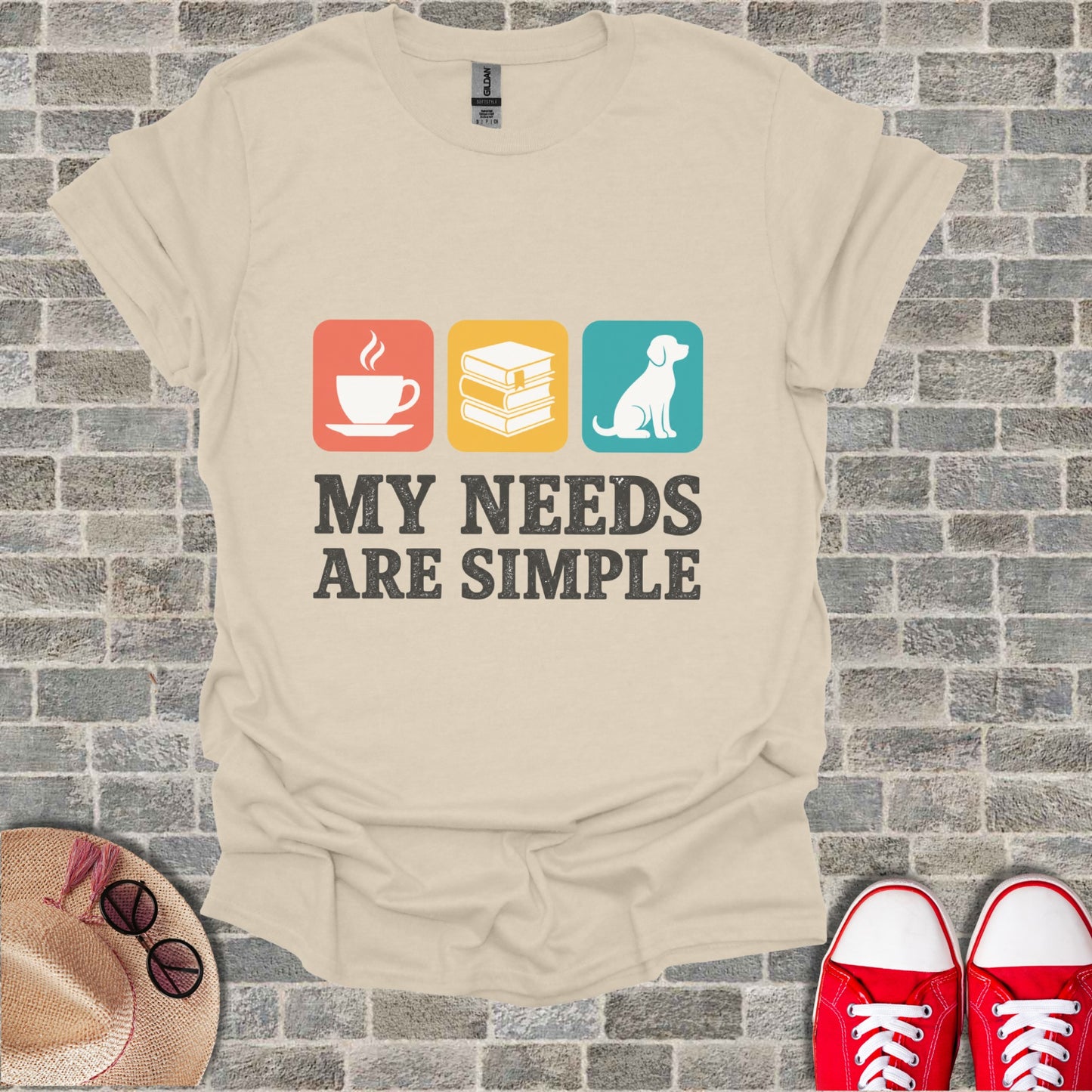 Light beige t-shirt with text "MY NEEDS ARE SIMPLE" and icons of coffee, books, and a dog.