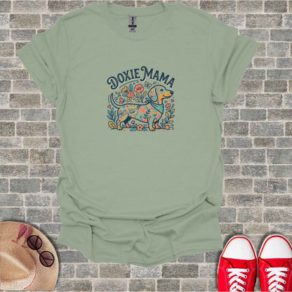 Dachshund and floral "Doxie Mama" graphic on a light green t-shirt.