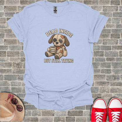 Light blue t-shirt with stuffed dog graphic reading "DEAD INSIDE BUT STILL TRYING".