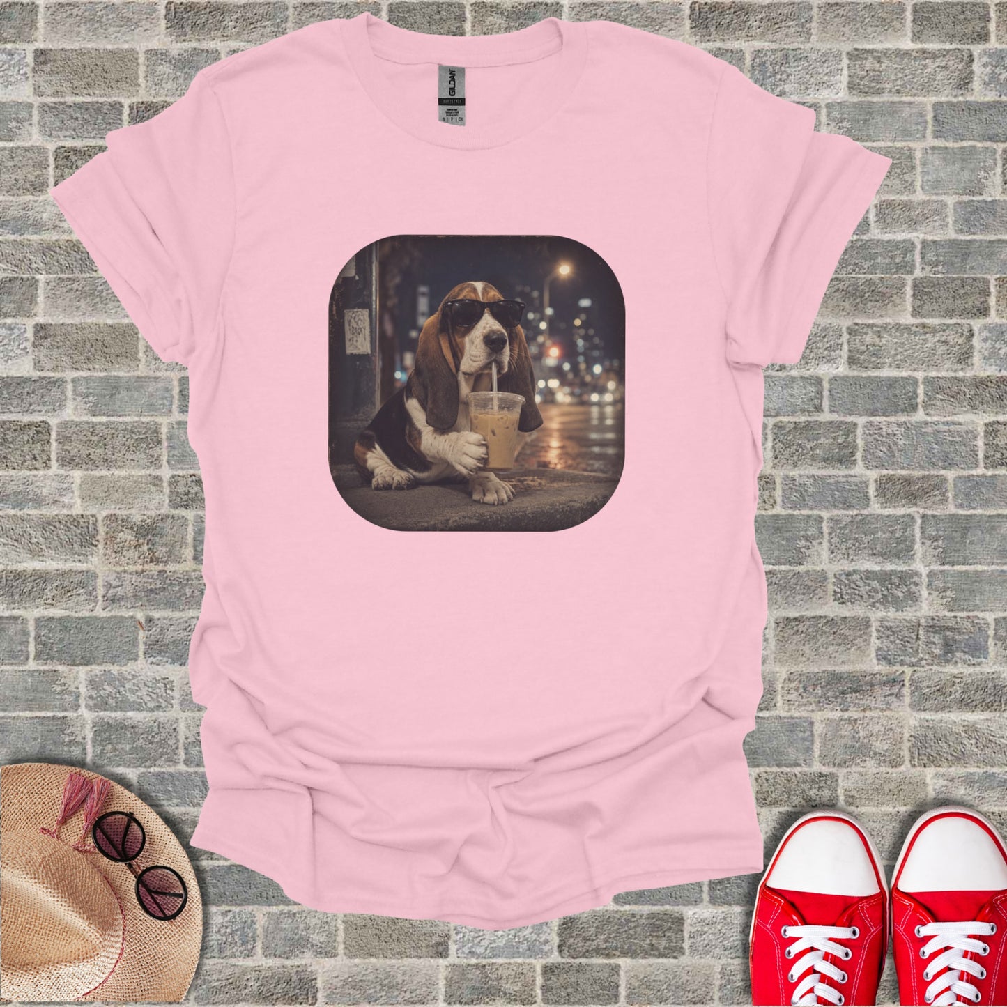 Pink t-shirt with a graphic of a Basset Hound wearing sunglasses drinking iced coffee.