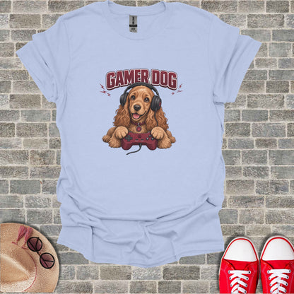Light blue t-shirt with a cartoon cocker spaniel wearing headphones and holding a video game controller.
