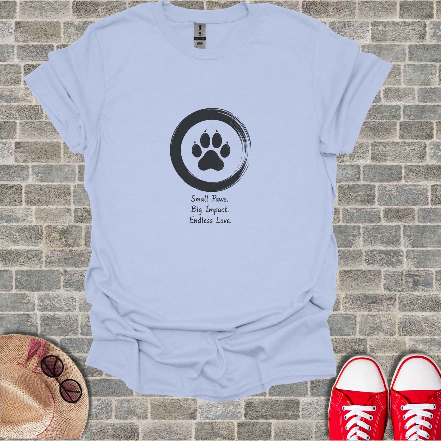 Light blue t-shirt with a black paw print logo and text: Small Paws. Big Impact. Endless Love.