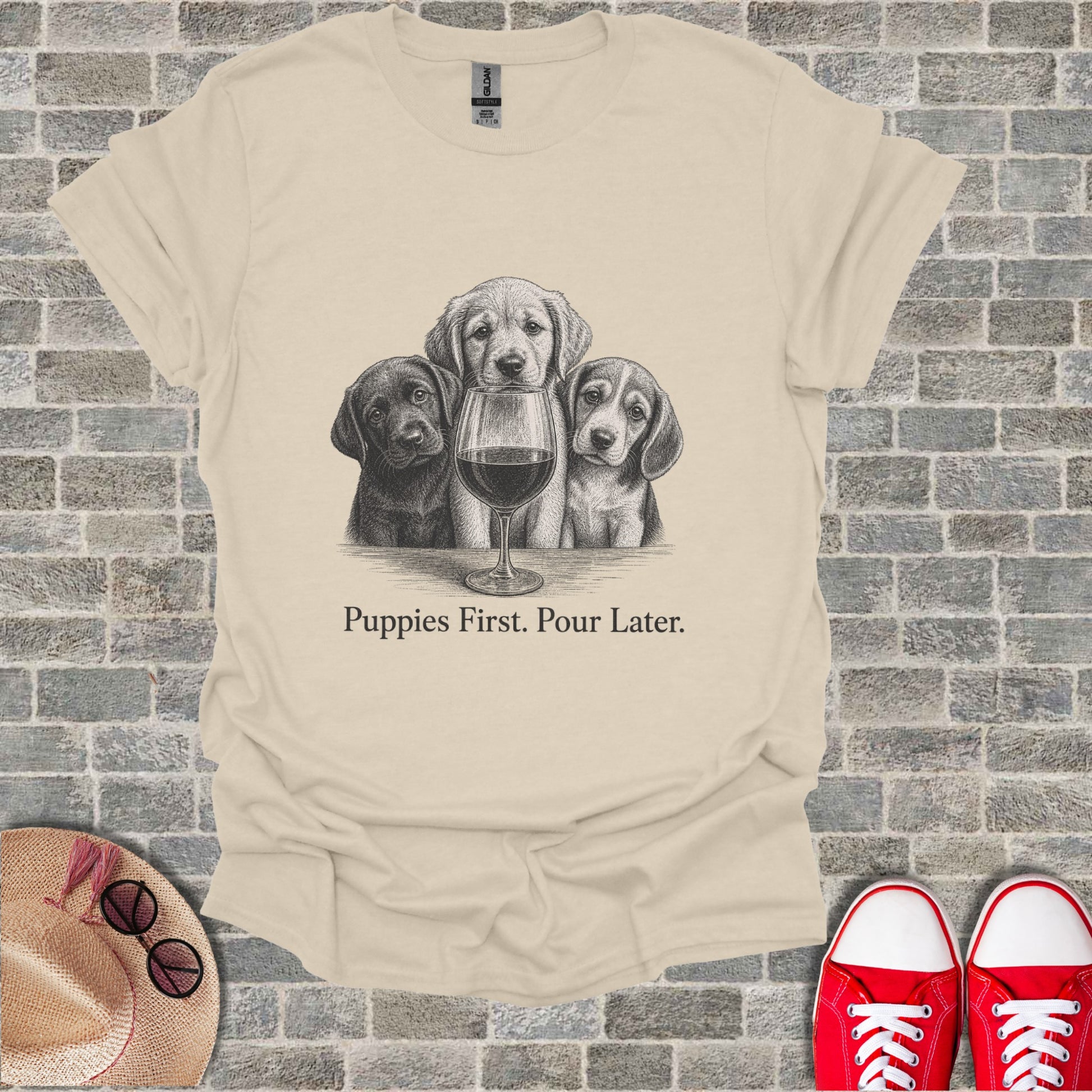 Cream t-shirt with black and white sketch of three puppies and a wine glass, text "Puppies First. Pour Later."