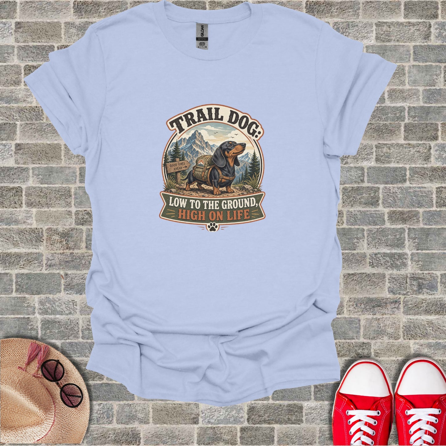 T-shirt with "Trail Dog: Low to the Ground, High on Life" text and mountain graphic.