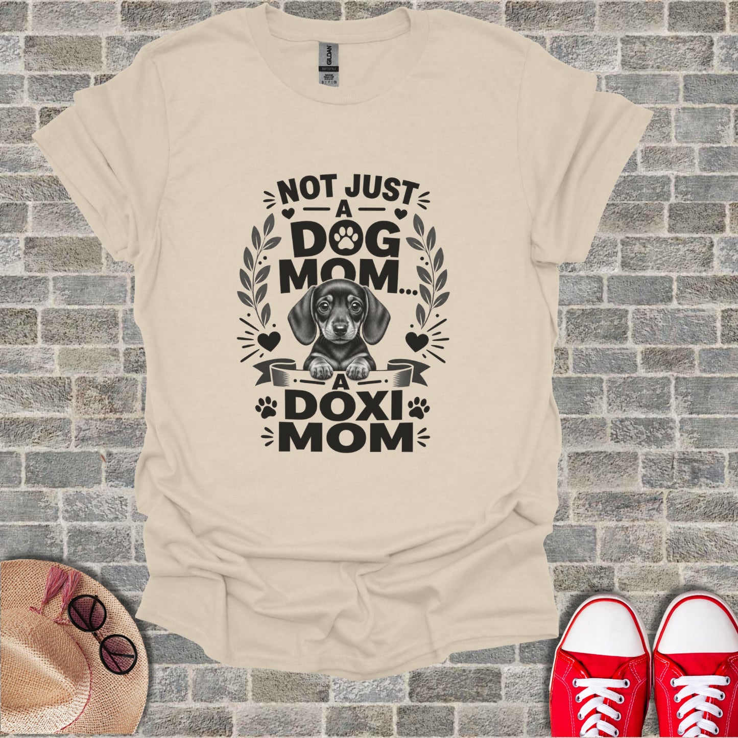 Cream t-shirt with black graphic of a dachshund and text "Not Just A Dog Mom... A Doxi Mom".