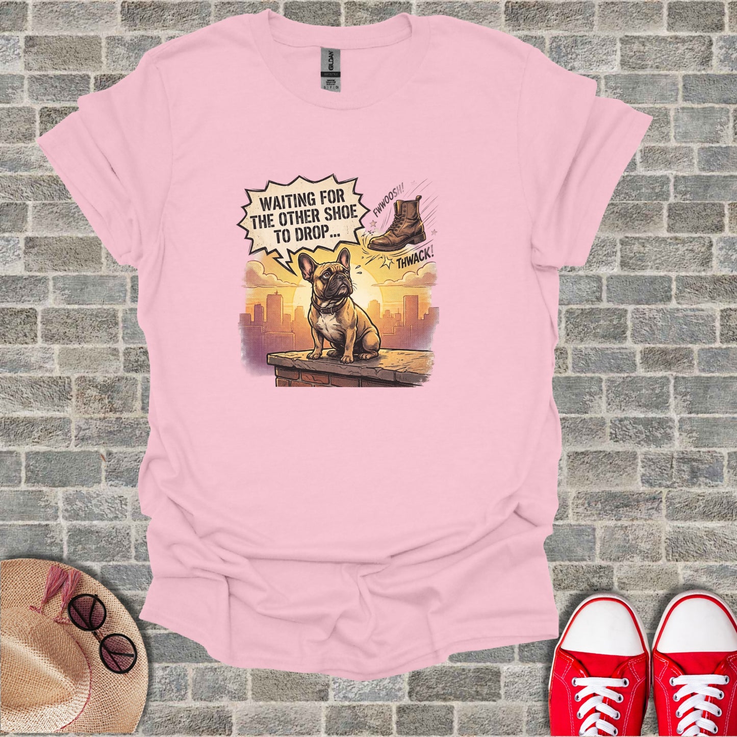 French Bulldog wearing a t-shirt with "Waiting for the other shoe to drop" text graphic.
