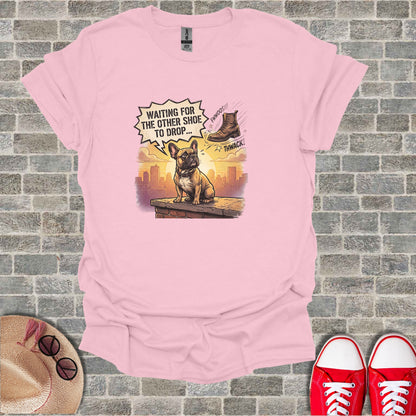 French Bulldog wearing a t-shirt with "Waiting for the other shoe to drop" text graphic.