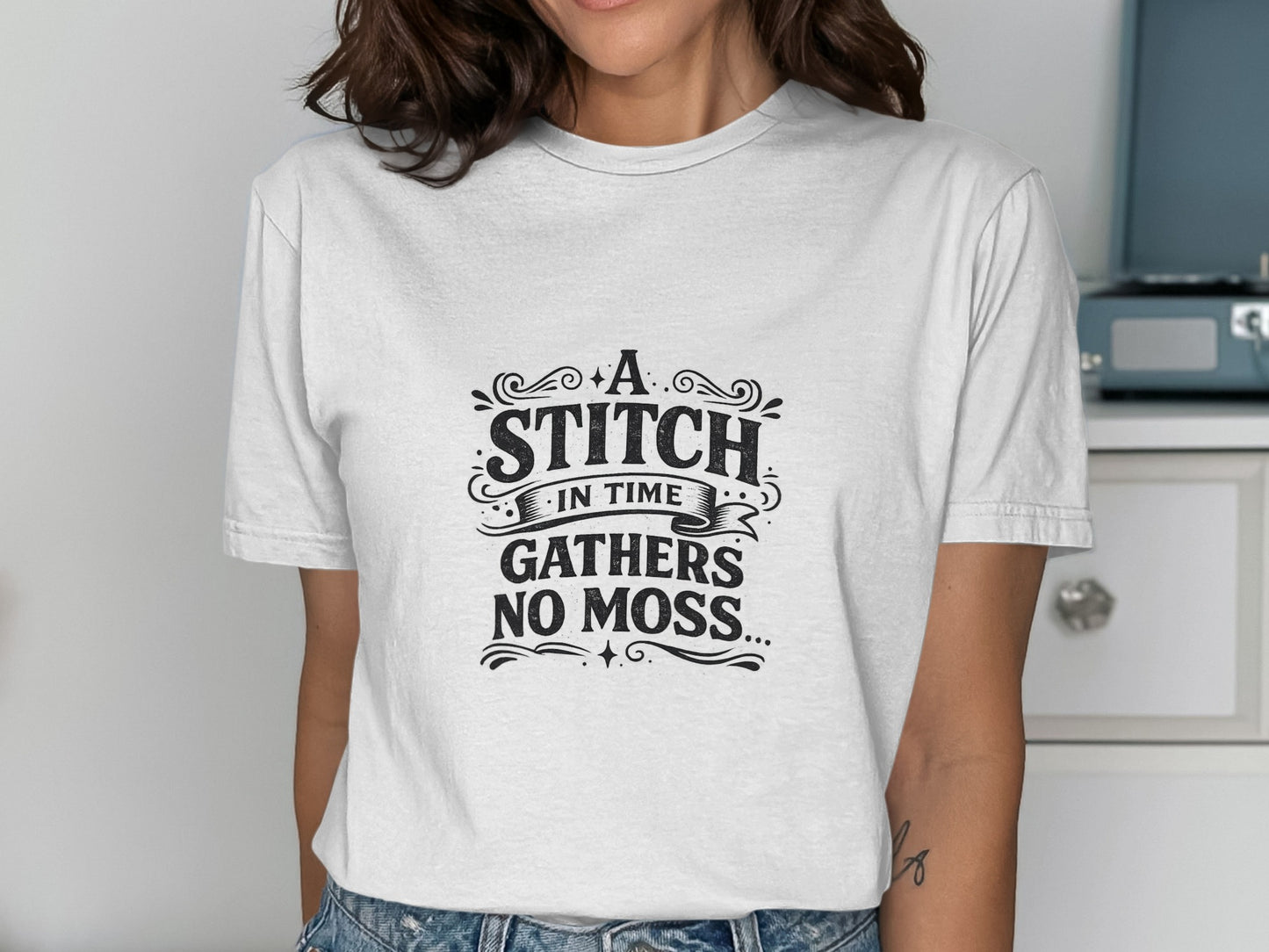 White t-shirt with "A stitch in time gathers no moss" text design.