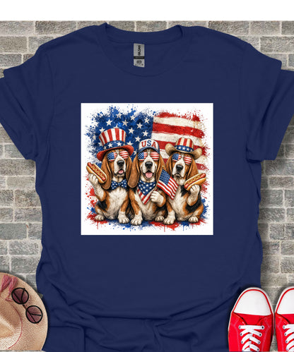 Three dogs in patriotic hats and sunglasses holding hot dogs and an American flag.
