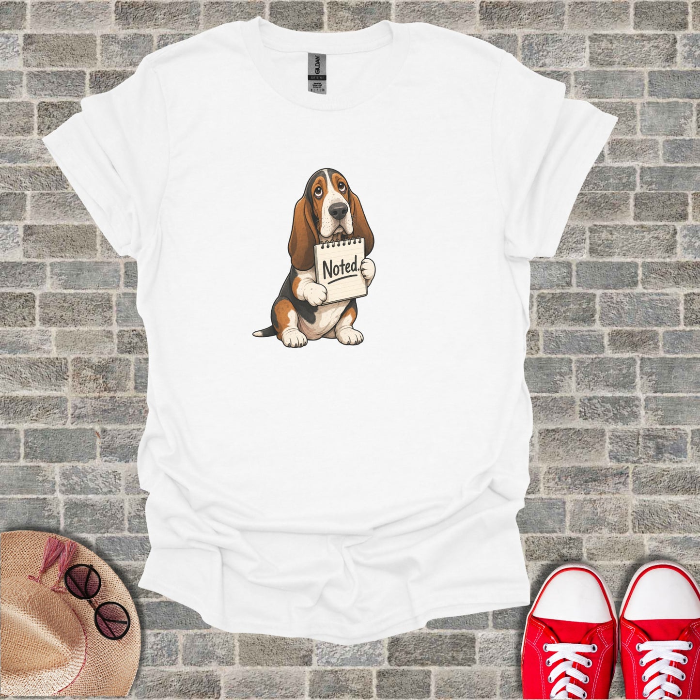 Basset Hound puppy holding a notepad with "Noted" written on it.