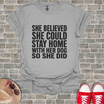 Gray t-shirt with black text "She believed she could stay home with her dog so she did."