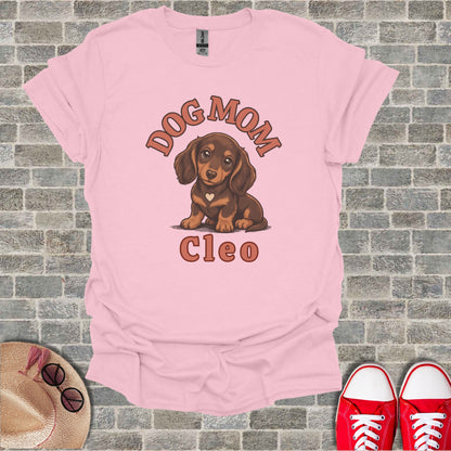 Pink t-shirt with cartoon dachshund wearing a heart, reads "DOG MOM Cleo."