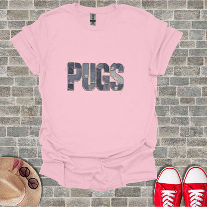 Pink t-shirt with "PUGS" text in denim patches and brick background.