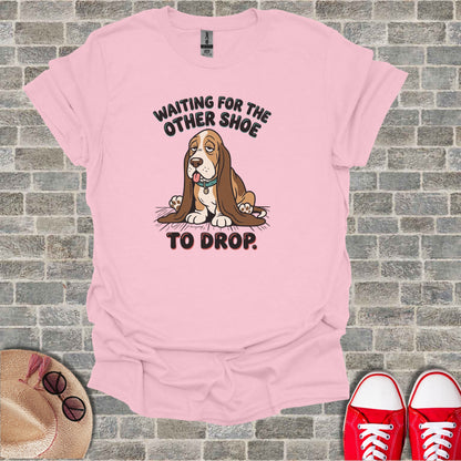 Pink t-shirt with cartoon dog and text "WAITING FOR THE OTHER SHOE TO DROP."