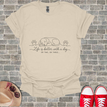 Cream t-shirt with line drawing of sleeping dog and paw prints. Text reads "Life is better with a dog OR TWO, OR THREE...".