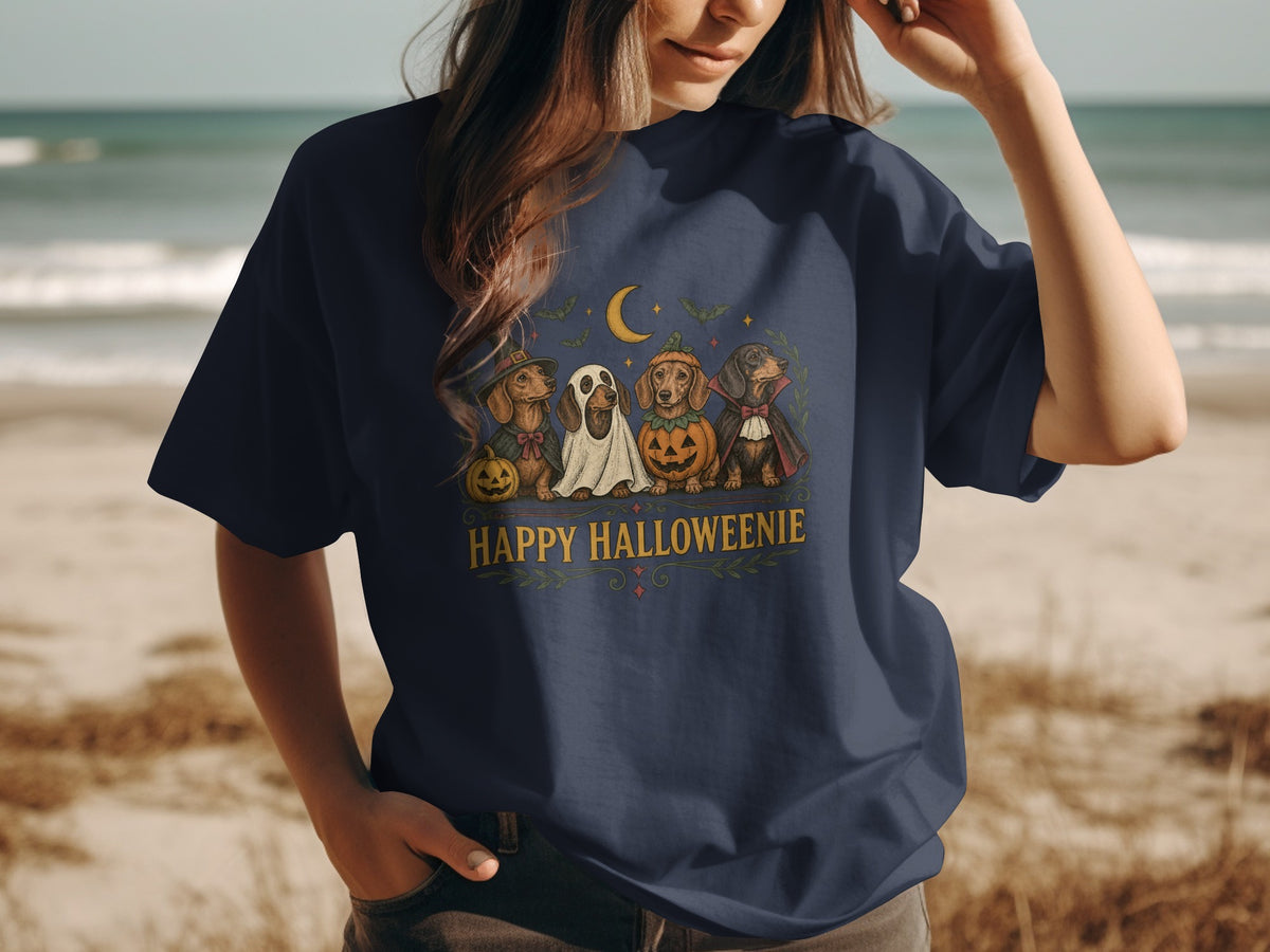 Dachshunds in Halloween costumes under a moon with text "Happy Halloweenie".