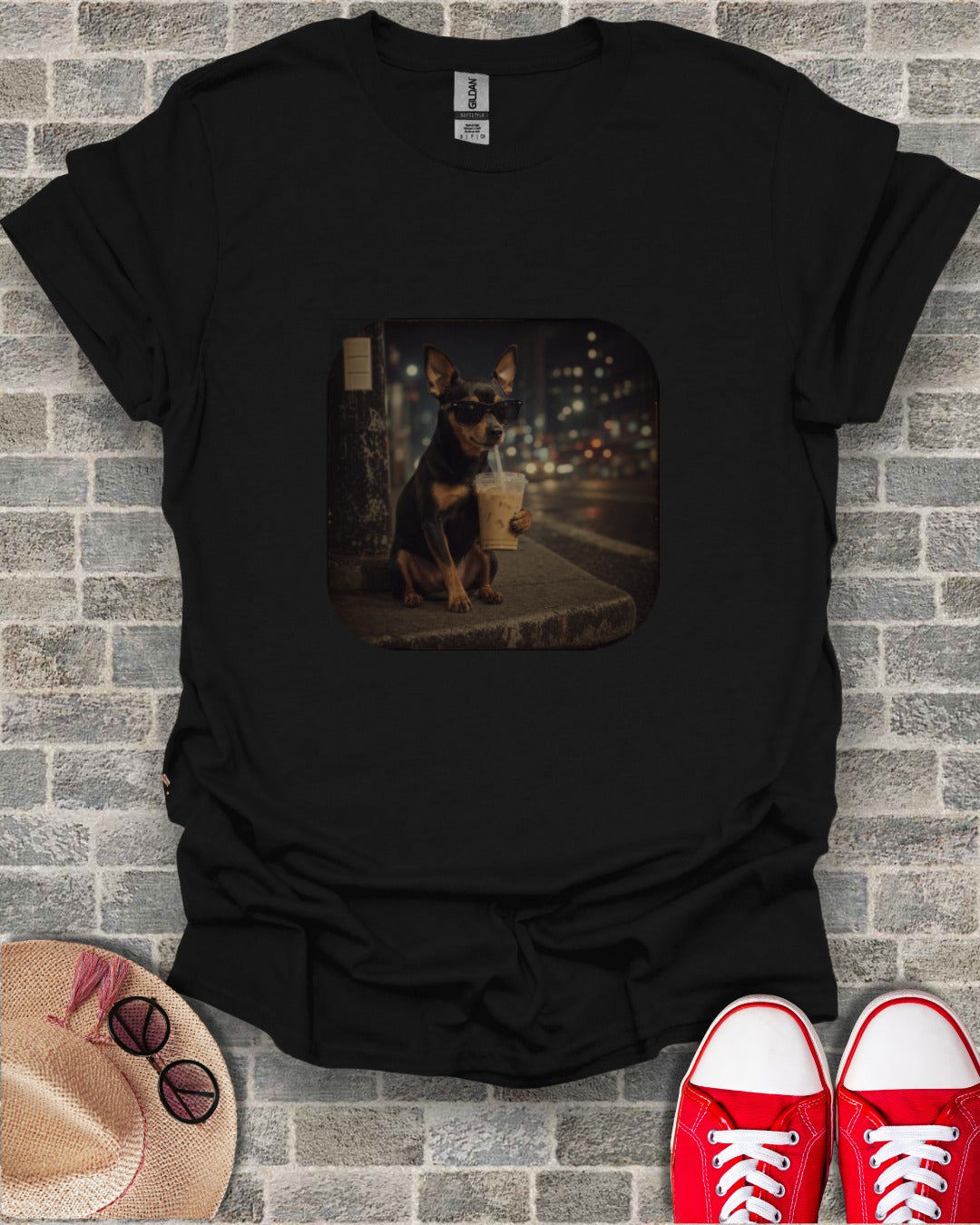 Small dog wearing sunglasses holds a coffee cup on a sidewalk at night.
