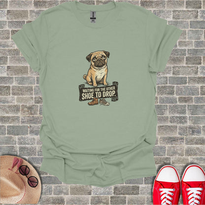 Pug wearing a shirt that says "Waiting for the other shoe to drop".