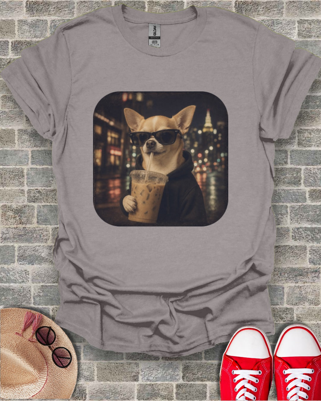 Chihuahua wearing sunglasses drinks iced coffee in front of blurry city lights.