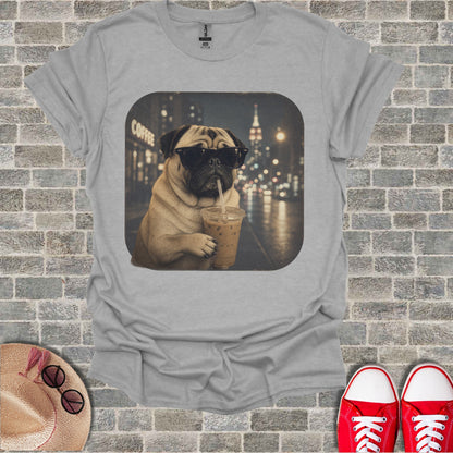 Pug wearing sunglasses drinks iced coffee in front of a city night scene.