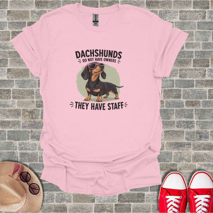Pink t-shirt with dachshund wearing sunglasses and text "Dachshunds do not have owners; they have staff."
