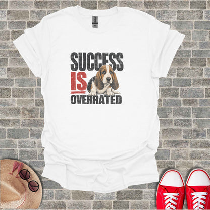 White t-shirt with "SUCCESS IS OVERRATED" text and a sad basset hound illustration.