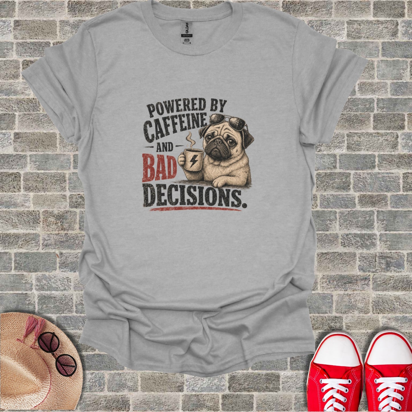Gray t-shirt with pug wearing sunglasses holding coffee cup, text "POWERED BY CAFFEINE AND BAD DECISIONS."