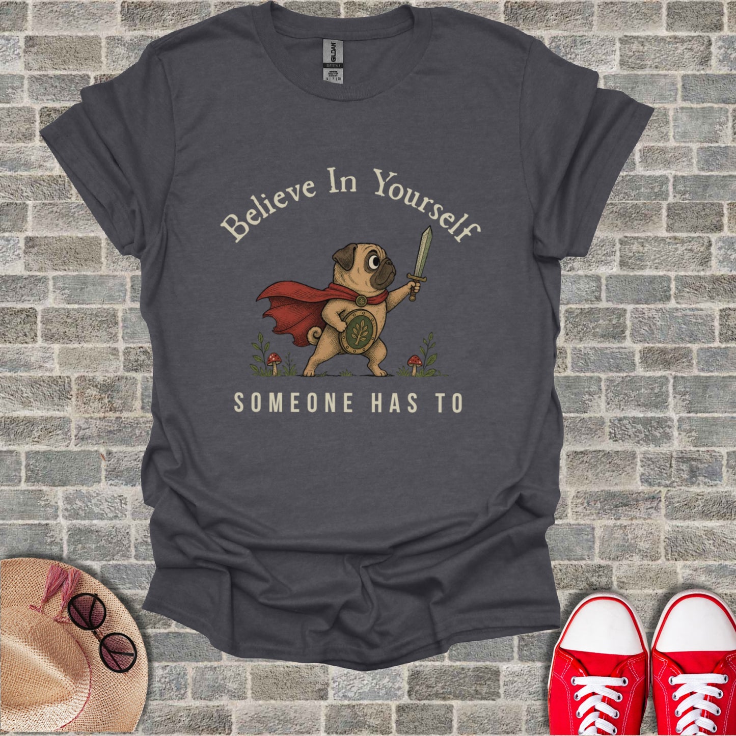 Pug wearing a cape and holding a sword, "Believe In Yourself Someone Has To."