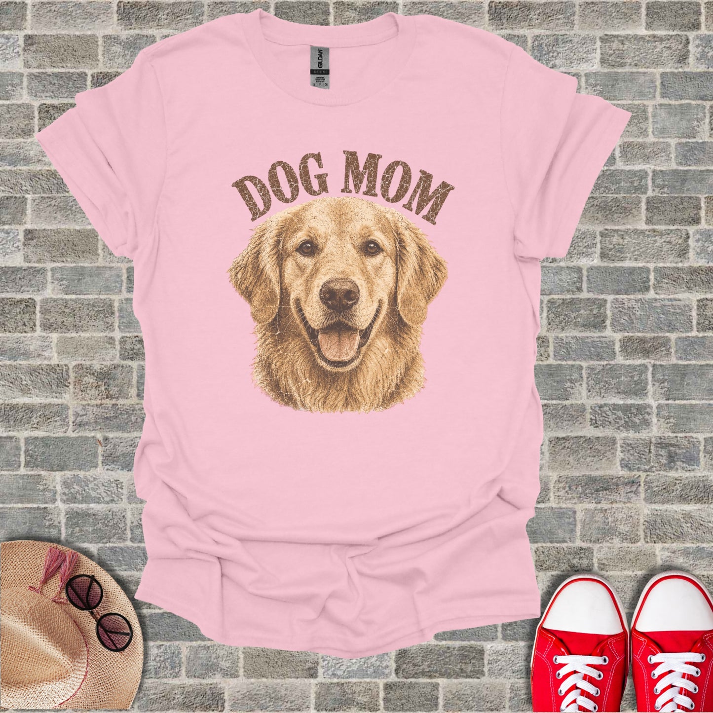 Pink t-shirt with golden retriever and "DOG MOM" text. Sneakers and hat visible.