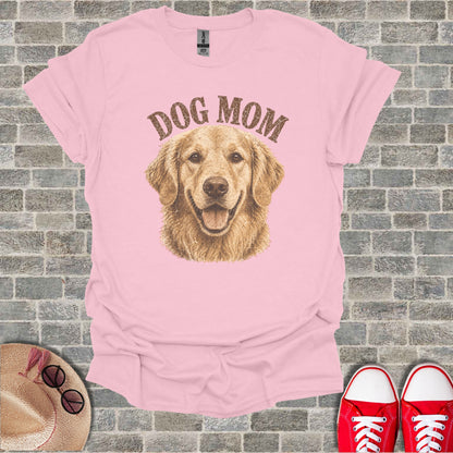 Pink t-shirt with golden retriever and "DOG MOM" text. Sneakers and hat visible.