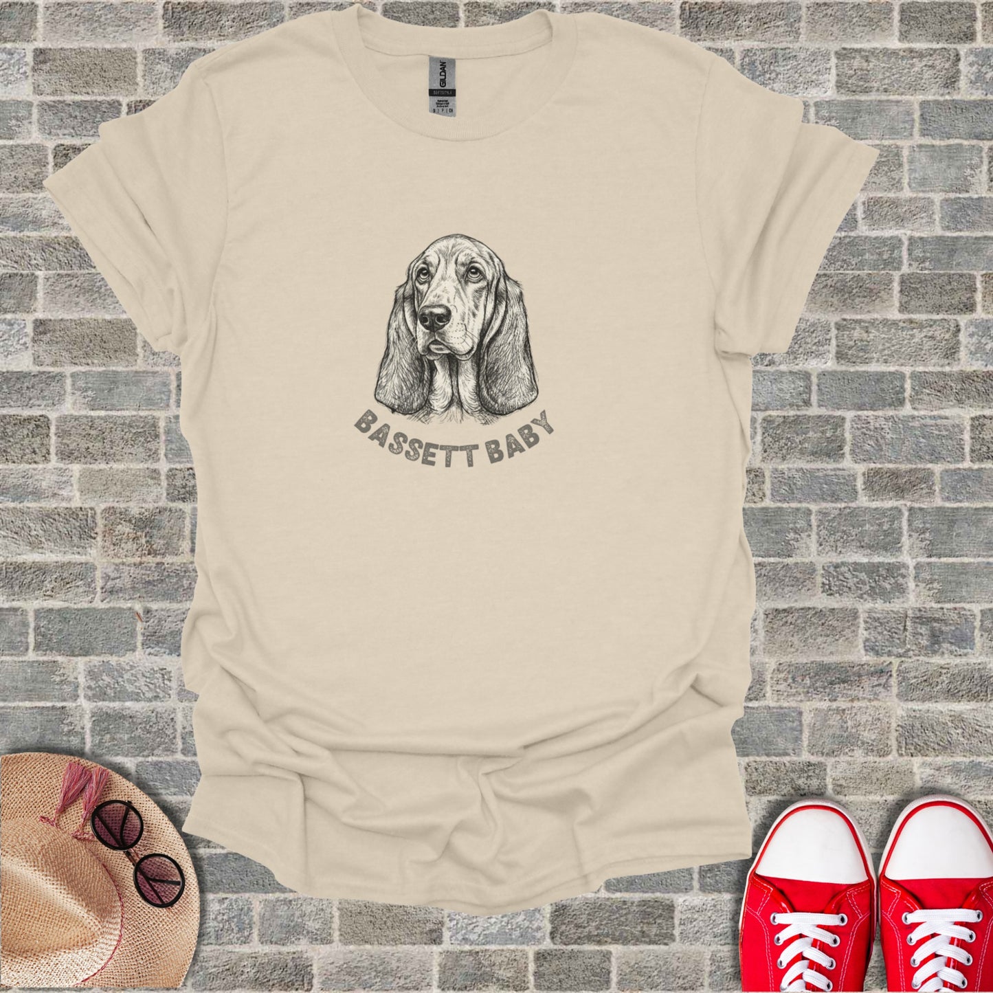Sketch of a Basset Hound's head with "BASSETT BABY" text on a cream t-shirt.