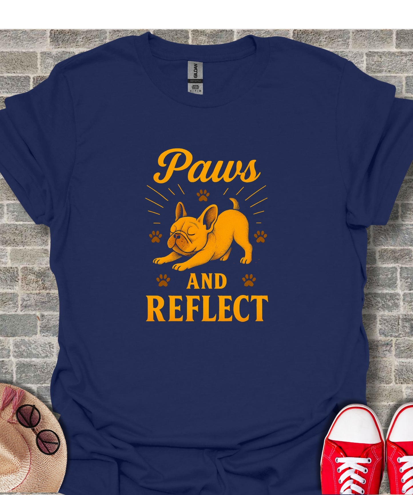 Dark blue t-shirt with orange French bulldog and text "Paws and Reflect".