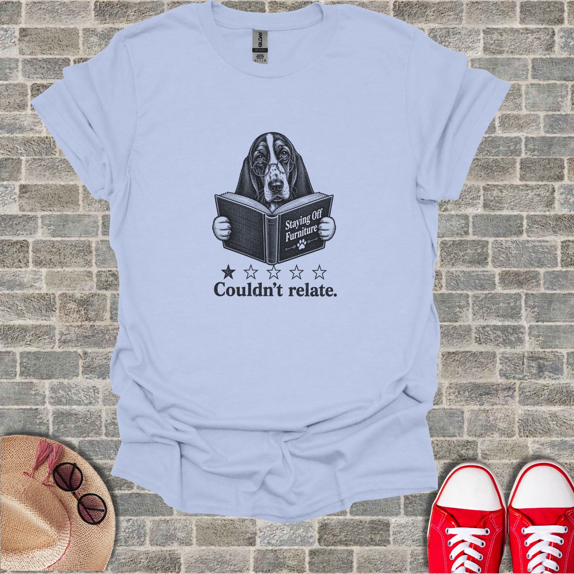 Basset hound wearing glasses reads a book titled "Staying Off Furniture" with "Couldn't relate." text.