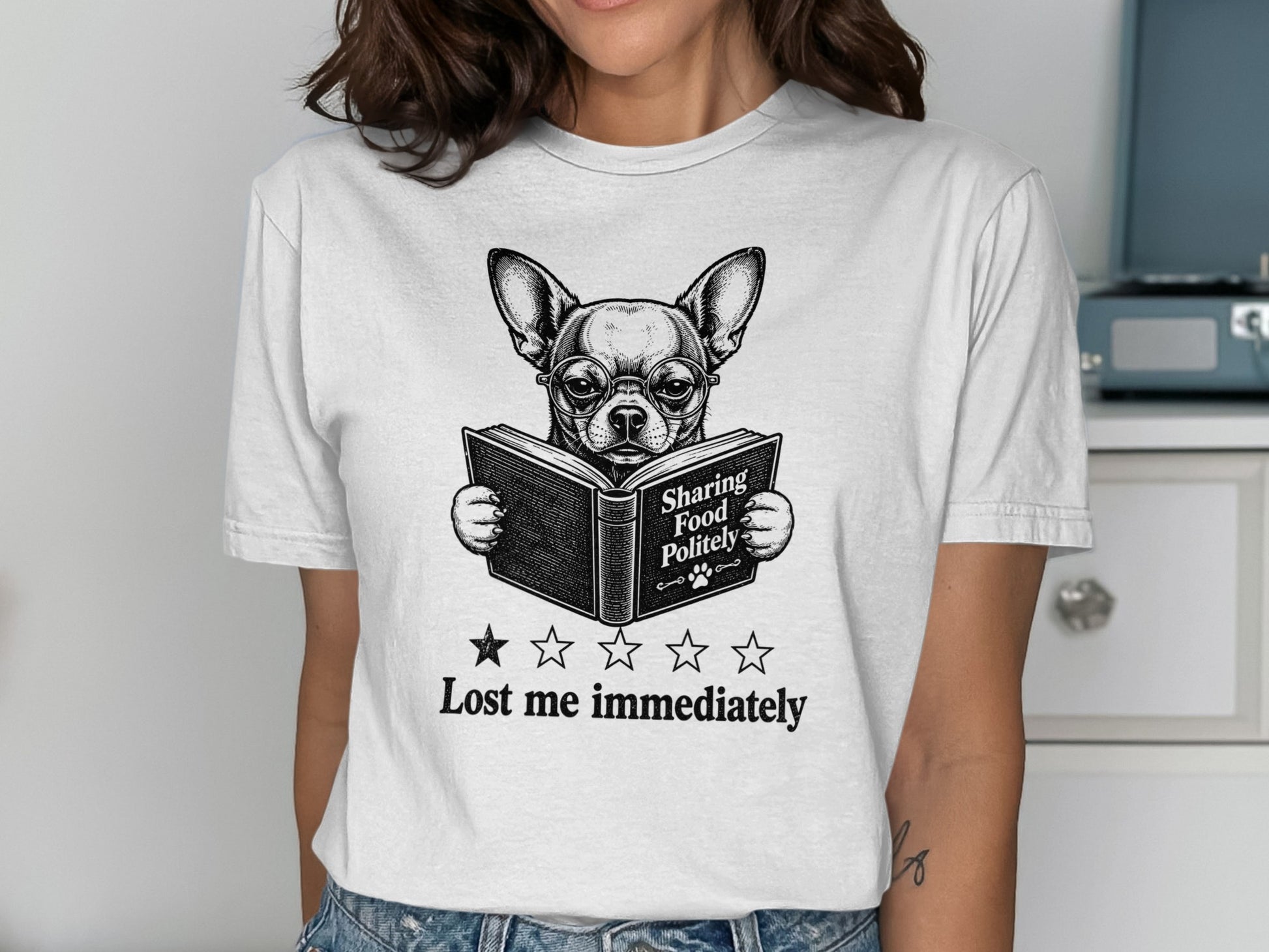 T-shirt graphic of a chihuahua wearing glasses reading a book, "Sharing Food Politely."