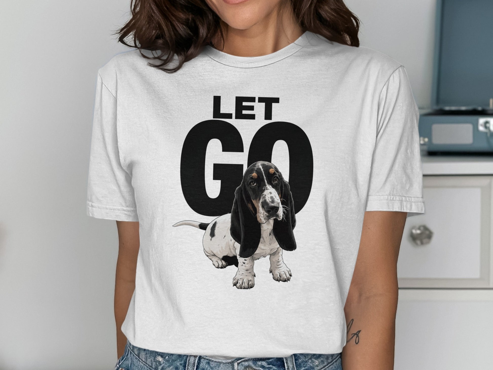 Woman wearing a white t-shirt with "LET GO" and a basset hound graphic.