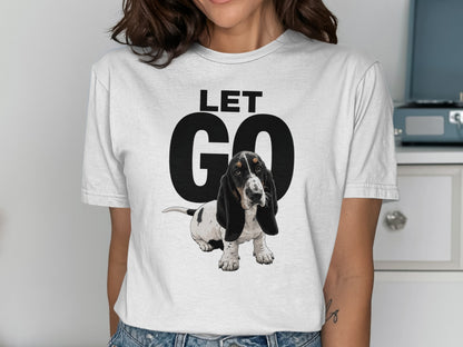 Woman wearing a white t-shirt with "LET GO" and a basset hound graphic.
