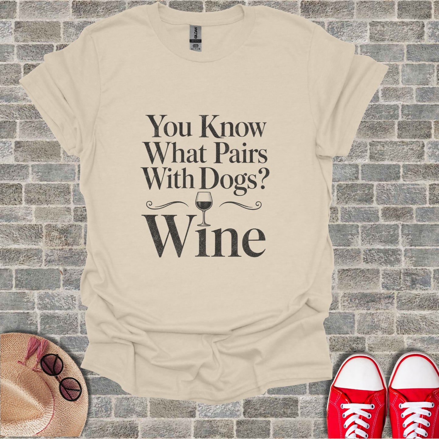Light tan t-shirt with black text and wine glass graphic reading "You Know What Pairs With Dogs? Wine."