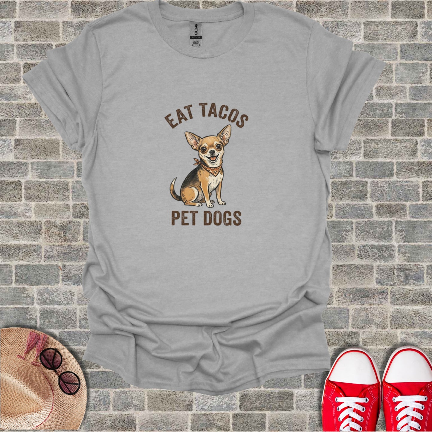 Grey t-shirt with illustration of a chihuahua and text "EAT TACOS PET DOGS".