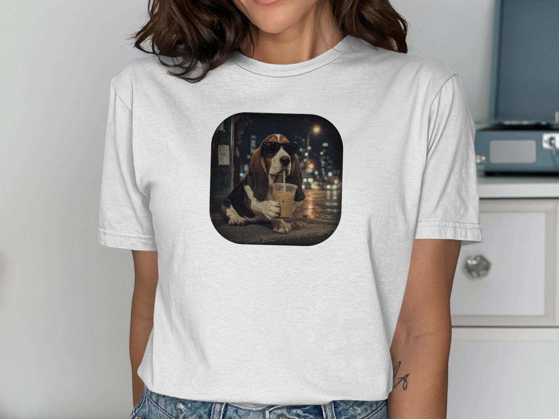 Basset hound wearing sunglasses drinks iced coffee on a street at night.