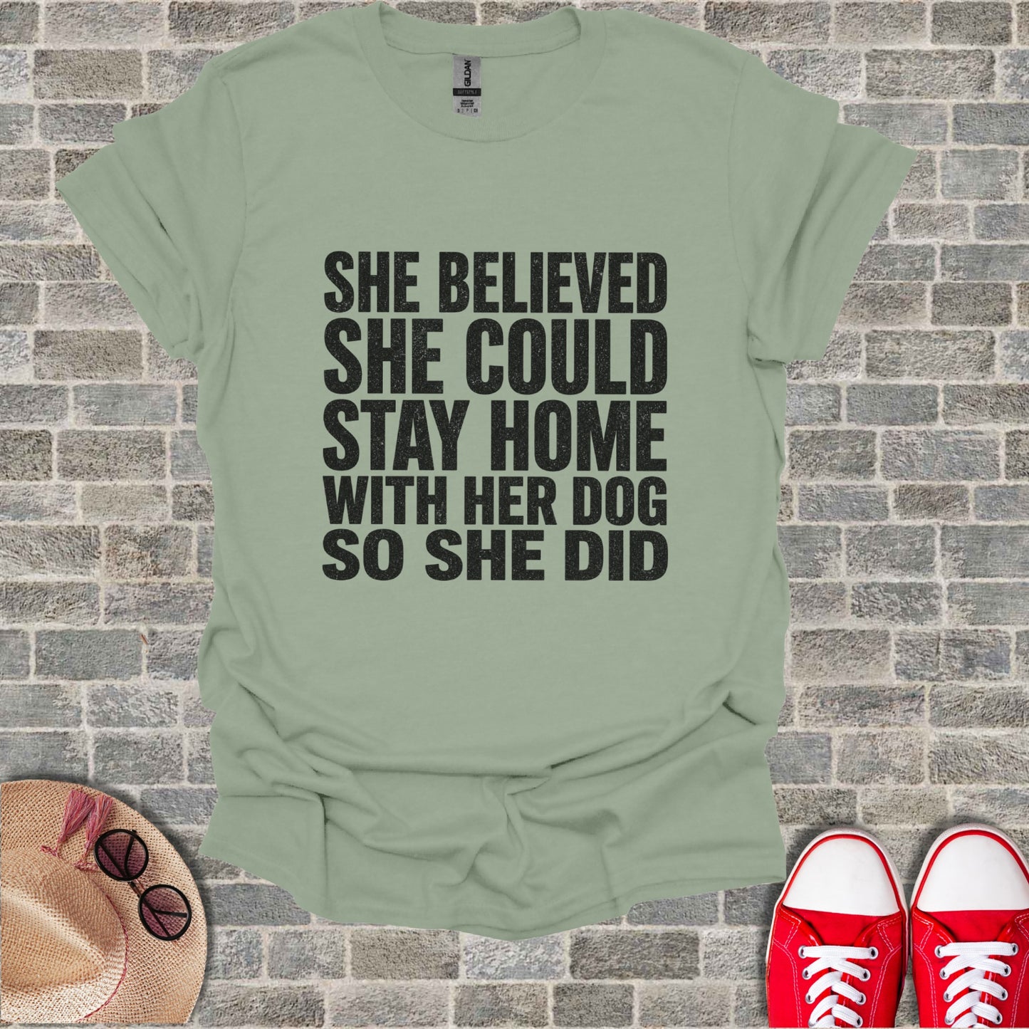 Light green t-shirt with black text saying "She believed she could stay home with her dog so she did".